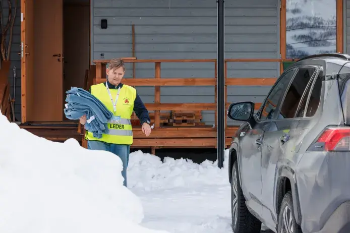 Frivillig Sanitetskvinne deler ut tepper under stengte veier pga snøskred