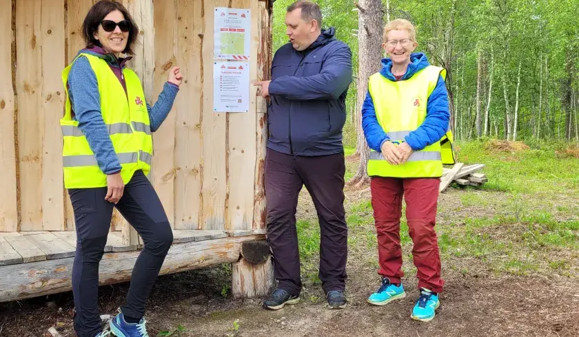 Tre mennesker på tur som henger nødplakater