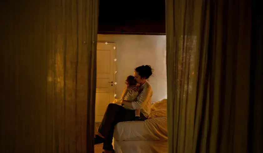 Mor som trøster barnet sitt i sengen uten tekst