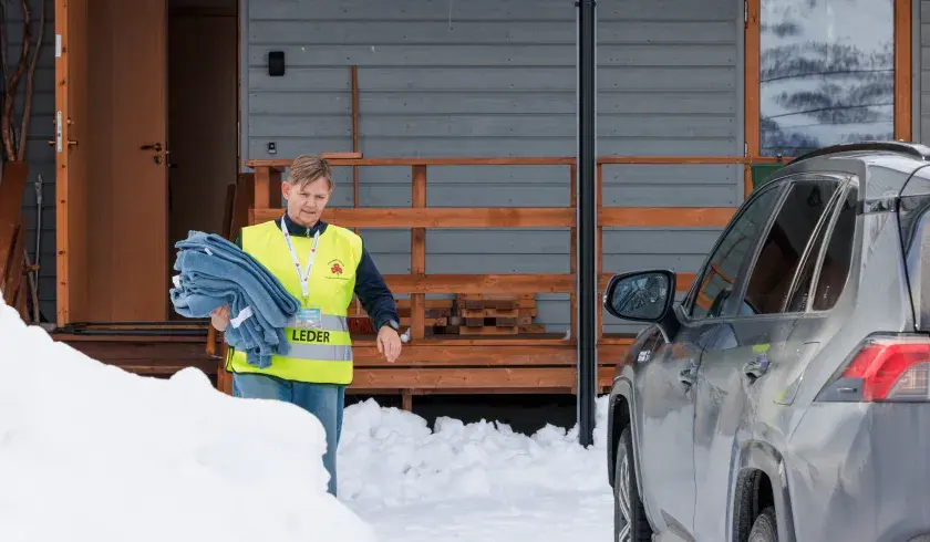 Frivillig Sanitetskvinne deler ut tepper under stengte veier pga snøskred