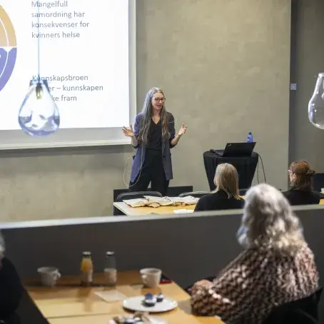 Seniorrådgiver på kvinnehelse Liv Bjørnhaug Johansen snakker foran salen full av mennesker om kvinnehelse på arbeidsplassen