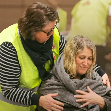 Tusen  - bildet av en eldre sanitetskvinnene som hjelpe en unge kvinne med et pledd